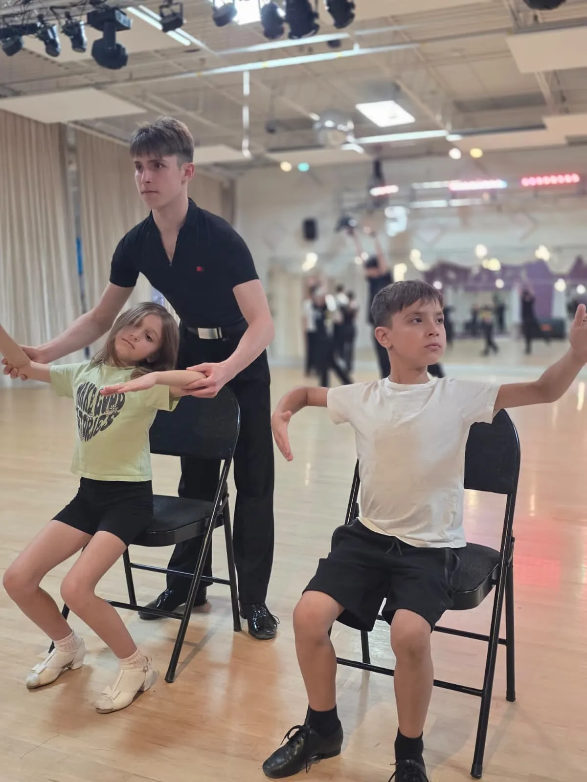 Andrey Ilyushenov teaching two children arm positions in a group class