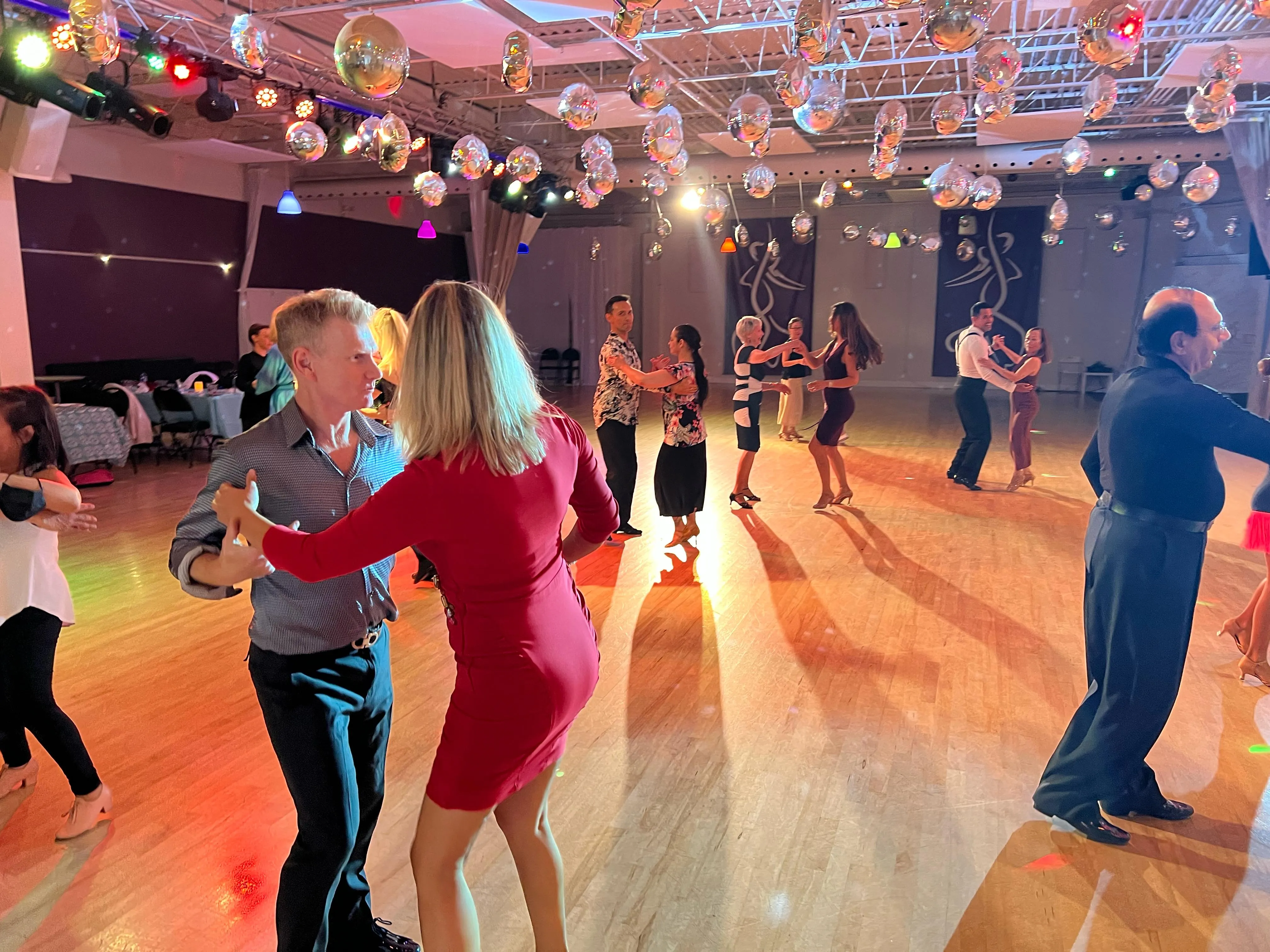Couples dancing at a social event under string lighting
