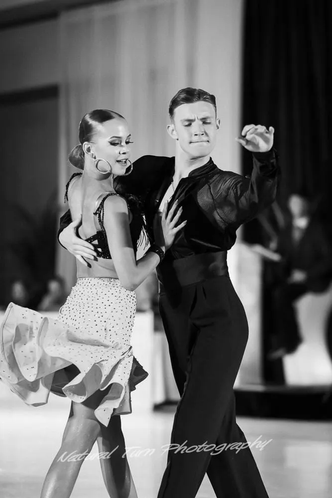 Black-and-white photo of Sophia Baydala and Andrey Ilyushenov dancing Latin at a competition