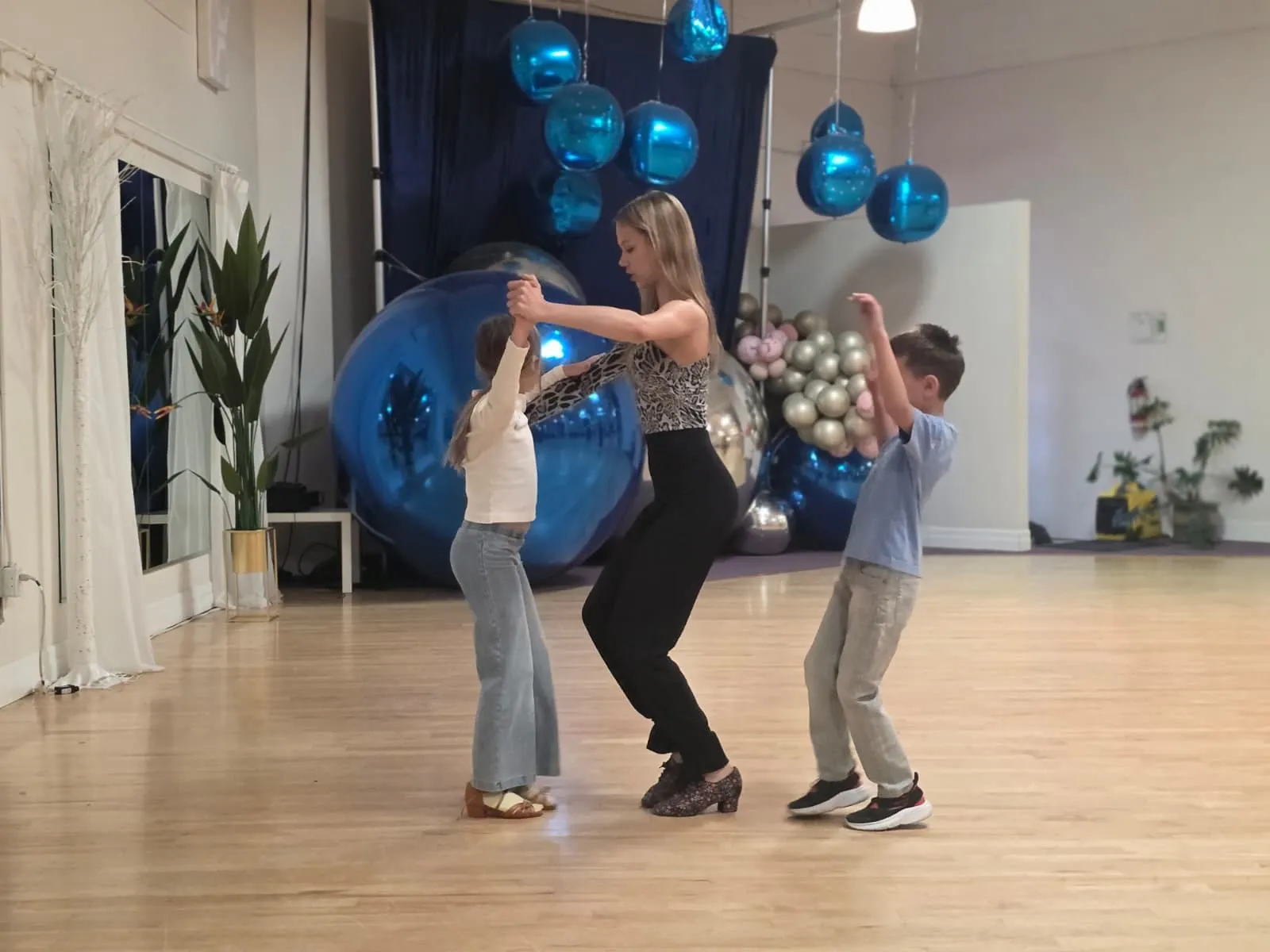 Sophia Baydala leading two children through a dance move in the studio